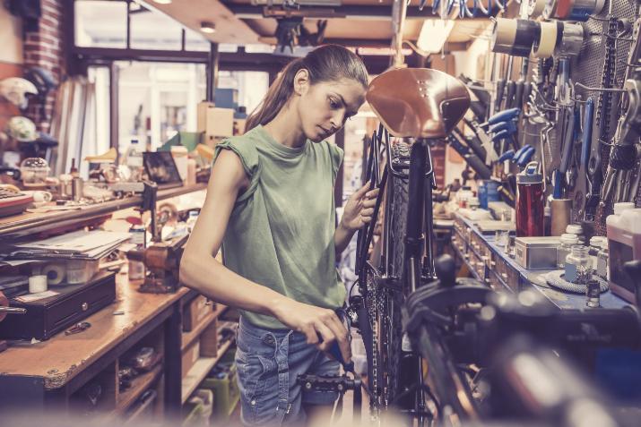 kuvassa nainen korjaa pyörää